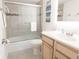 Clean bathroom with a framed-door shower/tub, a vanity with a sink, and a gray tile floor at 4151 S Atlantic Ave # 414, New Smyrna Beach, FL 32169