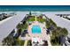 Aerial view of a community swimming pool with lounge chairs, palm trees, and apartment buildings near the ocean at 4225 S Atlantic Ave # 218, New Smyrna Beach, FL 32169