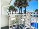 Balcony with chairs and table overlooks a pool area surrounded by palm trees on a sunny day at 4225 S Atlantic Ave # 218, New Smyrna Beach, FL 32169