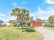 Charming single-story home with lush front lawn, mature palm trees, and a bright red garage door at 4350 Candlewood Ln, Ponce Inlet, FL 32127