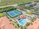 Scenic aerial view of a community pool and tennis courts near lush vegetation and housing at 460 Bouchelle Dr # 104, New Smyrna Beach, FL 32169