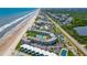 High aerial view showing condos nestled between tennis courts and the beach with ocean views at 4841 Saxon Dr # C201, New Smyrna Beach, FL 32169
