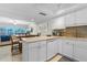 Open kitchen with white cabinetry, stainless appliances, and bar seating, flowing into the dining and living area at 4841 Saxon Dr # C201, New Smyrna Beach, FL 32169