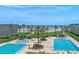 Balcony view of the pool area with two sparkling pools, ocean views, and swaying palm trees at 4841 Saxon Dr # C201, New Smyrna Beach, FL 32169