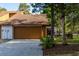 Charming home exterior featuring a brown garage door, well-manicured lawn, and mature trees at 5 Soco Trl, Ormond Beach, FL 32174
