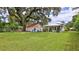 Spacious backyard with a large tree, a shed with a blue door, and a charming home with a cozy porch at 508 Faulkner St, New Smyrna Beach, FL 32168