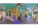 Inviting porch featuring a colorful ceiling, stone accents, ceiling fans, and a comfortable purple rocking chair at 508 Faulkner St, New Smyrna Beach, FL 32168