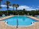 Community pool with clear blue water, plenty of lounge chairs, and surrounded by palm trees at 519 Aeolian Dr, New Smyrna Beach, FL 32168