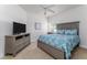 Bedroom with plush carpet, a ceiling fan, and stylish blue bedding on a queen bed, and a flat-screen television at 5300 S Atlantic Ave # 17-207, New Smyrna Beach, FL 32169