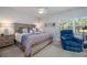 Comfortable bedroom featuring a ceiling fan, large window, and a cozy blue recliner at 5300 S Atlantic Ave # 17-207, New Smyrna Beach, FL 32169