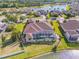 Aerial view of a home with a screened-in pool and lanai, surrounded by lush landscaping and a lake at 610 Mura Ct, New Smyrna Beach, FL 32168