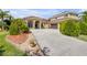 Long driveway leading to a tan home with a brown roof and an attached three-car garage at 610 Mura Ct, New Smyrna Beach, FL 32168