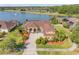Aerial view of a tan home with a brown roof with a lake in the backyard at 610 Mura Ct, New Smyrna Beach, FL 32168