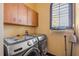 Functional laundry room with modern washer, dryer, upper cabinets, and window at 610 Mura Ct, New Smyrna Beach, FL 32168