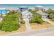 Aerial shot of a coastal house surrounded by lush greenery and other charming homes, with the ocean in the background at 6361 Turtlemound Rd, New Smyrna Beach, FL 32169
