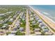 An aerial view capturing a stretch of beachfront homes nestled between ocean and marsh at 6361 Turtlemound Rd, New Smyrna Beach, FL 32169