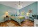 Bright bedroom with a tropical-themed bed, two windows, a ceiling fan, hardwood floors and sitting chair at 6361 Turtlemound Rd, New Smyrna Beach, FL 32169