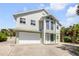 Inviting two-story coastal home with a two-car garage, lush tropical landscaping, and a well-manicured lawn at 6361 Turtlemound Rd, New Smyrna Beach, FL 32169