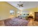 Bright primary bedroom with hardwood floors, two windows, a ceiling fan and a patterned area rug at 6361 Turtlemound Rd, New Smyrna Beach, FL 32169