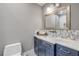 Bathroom featuring blue vanity with white marble countertop, decorative backsplash, toilet, and large mirror at 6771 Turtlemound Rd, New Smyrna Beach, FL 32169