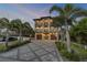 Elegant three-story home boasting balconies and a patterned driveway, framed by palm trees at 6771 Turtlemound Rd, New Smyrna Beach, FL 32169