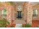 Home's arched entrance with brick features, black door with wreath, and manicured plants at 682 Ferncliff Dr, Port Orange, FL 32127
