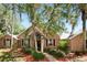 Charming single-story brick home with arched windows, lush landscaping, and mature trees at 682 Ferncliff Dr, Port Orange, FL 32127