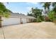 Three car garage with large driveway, brick exterior, and professional landscaping at 682 Ferncliff Dr, Port Orange, FL 32127