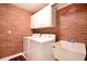 Laundry room with red brick walls, cabinets, sink and a red and black rug on the floor at 682 Ferncliff Dr, Port Orange, FL 32127