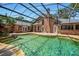 Screen-enclosed swimming pool with waterfall, home architecture, and a brick fireplace at 682 Ferncliff Dr, Port Orange, FL 32127
