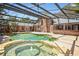Outdoor pool and jacuzzi, screened in, with backyard bar and brick home in background at 682 Ferncliff Dr, Port Orange, FL 32127