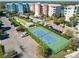Aerial view of a blue and green tennis court and parking area at a condo complex with colorful buildings at 7 Riverwalk Dr # 205, New Smyrna Beach, FL 32169