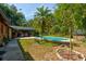 Lush backyard featuring a pool, patio, and mature trees, perfect for outdoor living at 706 S Timberlane Dr, New Smyrna Beach, FL 32168