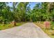 Long driveway lined with brick columns and a rustic fence, leading to a secluded property surrounded by trees at 706 S Timberlane Dr, New Smyrna Beach, FL 32168