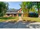 Inviting brick home with a vibrant turquoise door, surrounded by lush greenery, offering a warm and welcoming curb appeal at 706 S Timberlane Dr, New Smyrna Beach, FL 32168