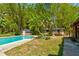 Backyard with a sparkling pool, lush bamboo, and a pool house surrounded by greenery at 706 S Timberlane Dr, New Smyrna Beach, FL 32168
