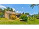 Well-maintained backyard showcasing a spacious lawn, mature landscaping, and a charming exterior facade for curb appeal at 706 Sky Tree Ct, New Smyrna Beach, FL 32168