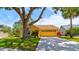 Charming yellow single-story home featuring a well-manicured lawn, a large tree, and an attached two-car garage at 706 Sky Tree Ct, New Smyrna Beach, FL 32168