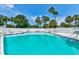 Community swimming pool featuring lounge chairs, tables and lush tropical landscaping at 706 Sky Tree Ct, New Smyrna Beach, FL 32168