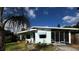 Exterior shot of the home, showcasing the facade, screen porch, and mature landscaping under a sunny sky at 114 Hickory St, New Smyrna Beach, FL 32168