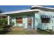 Exterior of home featuring light blue paint, blue door, awning, and lush front lawn at 114 Hickory St, New Smyrna Beach, FL 32168