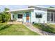 Charming home featuring a quaint blue door, awning, and well-manicured lawn with a stepping-stone walkway at 114 Hickory St, New Smyrna Beach, FL 32168