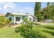 A charming home with a well-kept lawn, complemented by mature trees and a colorful garden at 114 Hickory St, New Smyrna Beach, FL 32168