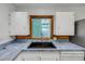 This kitchen features a stainless steel faucet and black sink under a window with white cabinets and blue counters at 114 Hickory St, New Smyrna Beach, FL 32168