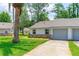 A single-story home shows a gray garage door, well-kept lawn, and small bushes at 115 Bob White Ct, Daytona Beach, FL 32119