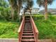 Backyard staircase leading to a home with screened in pool, lush landscaping, and a dock at 128 Godfrey Rd, Edgewater, FL 32141