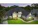 Beautiful two-story home at dusk featuring gray brick accents, landscape lighting, and a green lawn at 128 Godfrey Rd, Edgewater, FL 32141