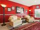 Bright red living room featuring light yellow armchairs, dark-stained wood trim, and ornate area rug at 128 Godfrey Rd, Edgewater, FL 32141
