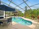 Inviting screened pool area with a spa, patio furniture, and lush landscaping at 128 Godfrey Rd, Edgewater, FL 32141