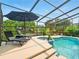 Relaxing screened-in pool and spa area with comfortable lounge chairs and tropical landscaping at 128 Godfrey Rd, Edgewater, FL 32141